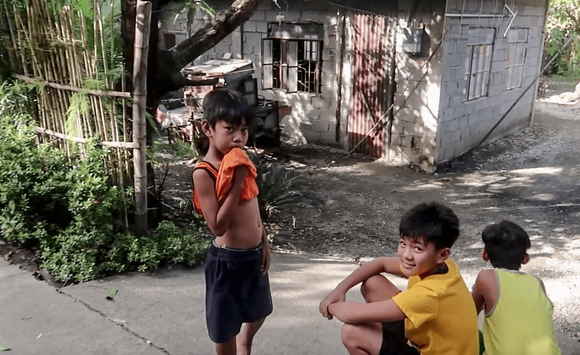 shy filipino boys smiling to foreigner in a typical barangay in the philippines